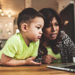 child and parent using a laptop